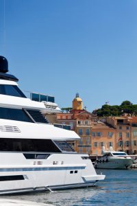 A luxury boat leaves St Tropez Harbour on the French Riviera. The iconic landmark of St Tropez, the church tower of Notre Dame of the Assumption church is in the background. Good copy space.